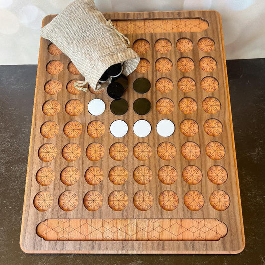 Wooden game board with circular holes and a bag of black and white stones on a dark surface.