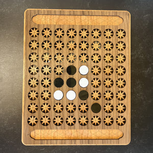 Wooden puzzle board with star patterns and circular cutouts on a dark surface