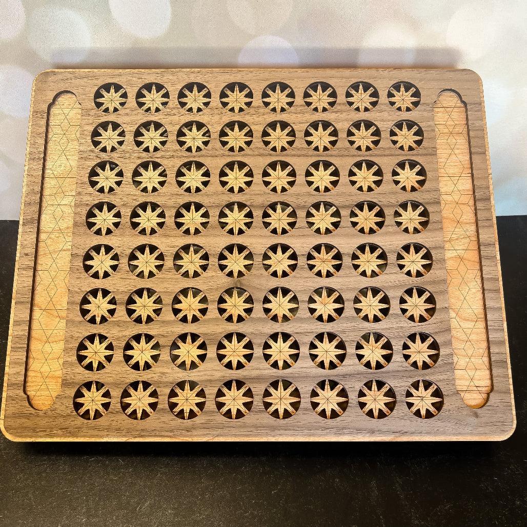 Wooden tray with star-shaped holes and a wooden handle on a dark surface.