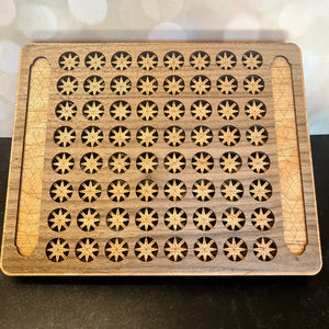 Wooden tray with star-shaped holes and a wooden handle on a dark surface.