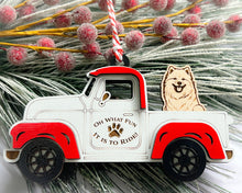 Load image into Gallery viewer, A vintage style red and white truck ornament with a dog riding in the back seat, placed on a branch with Christmas decorations.