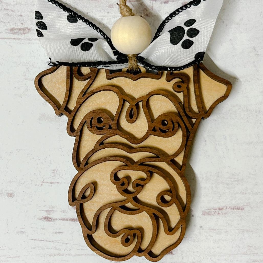 Laser-cut wooden doodle art dog ornament with paw print ribbon bow and bead, hanging on rustic twine.