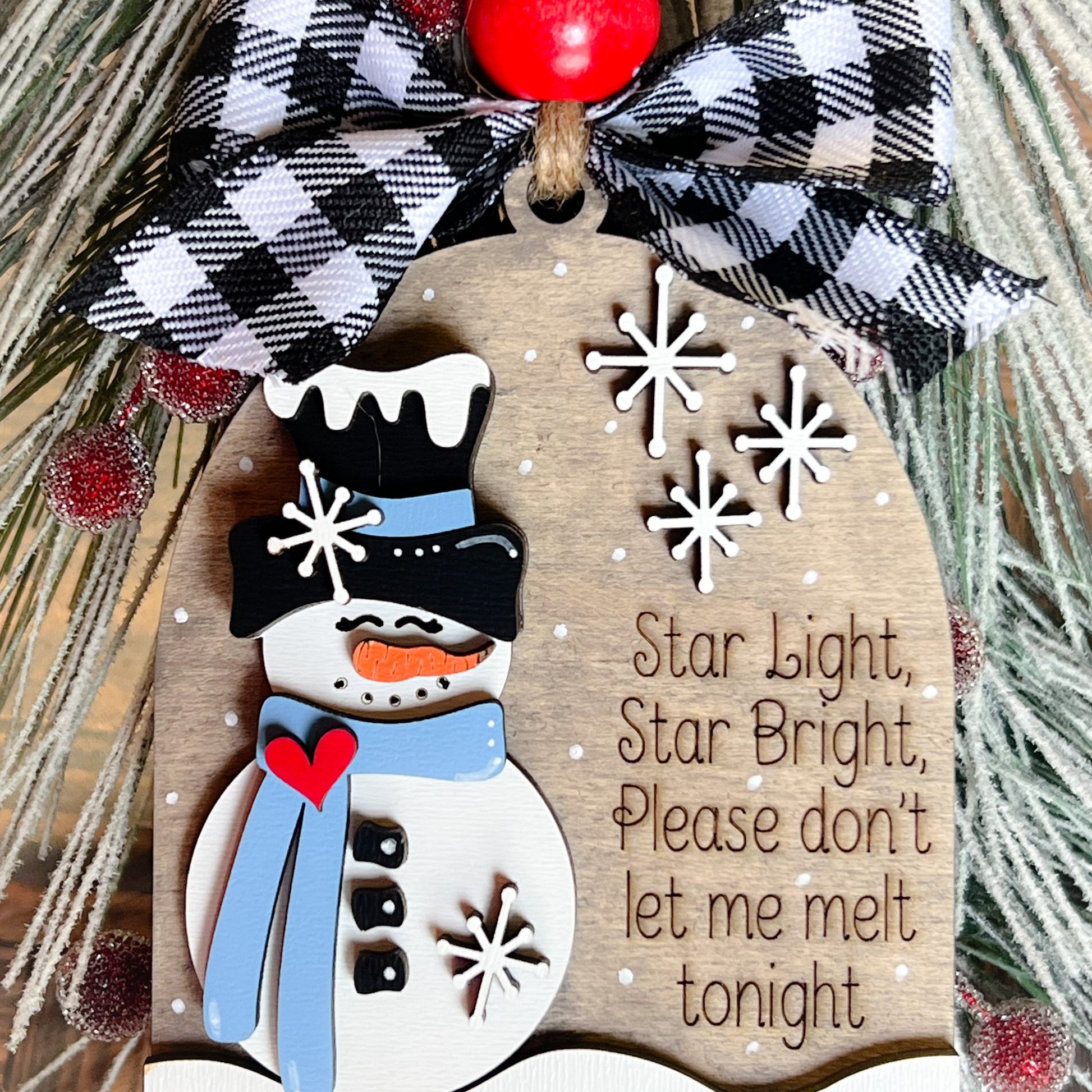 A decorative snowman ornament with a poem, black and white checkered bow, and red bead.