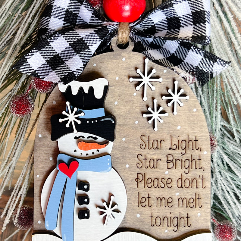 A decorative snowman ornament with a poem, black and white checkered bow, and red bead.