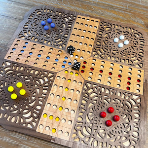Wooden game board with decorative patterns and colorful game pieces on a wooden surface.