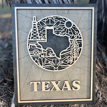 Load image into Gallery viewer, A laser-cut wooden sign or ornament with a silhouette of Texas and iconic symbols, including an oil rig, desert cacti, and the Texas sun. The word &#39;TEXAS&#39; is prominently displayed at the bottom.