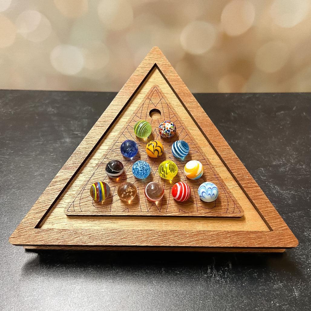 Triangle wooden marble solitaire game board filled with colorful marbles