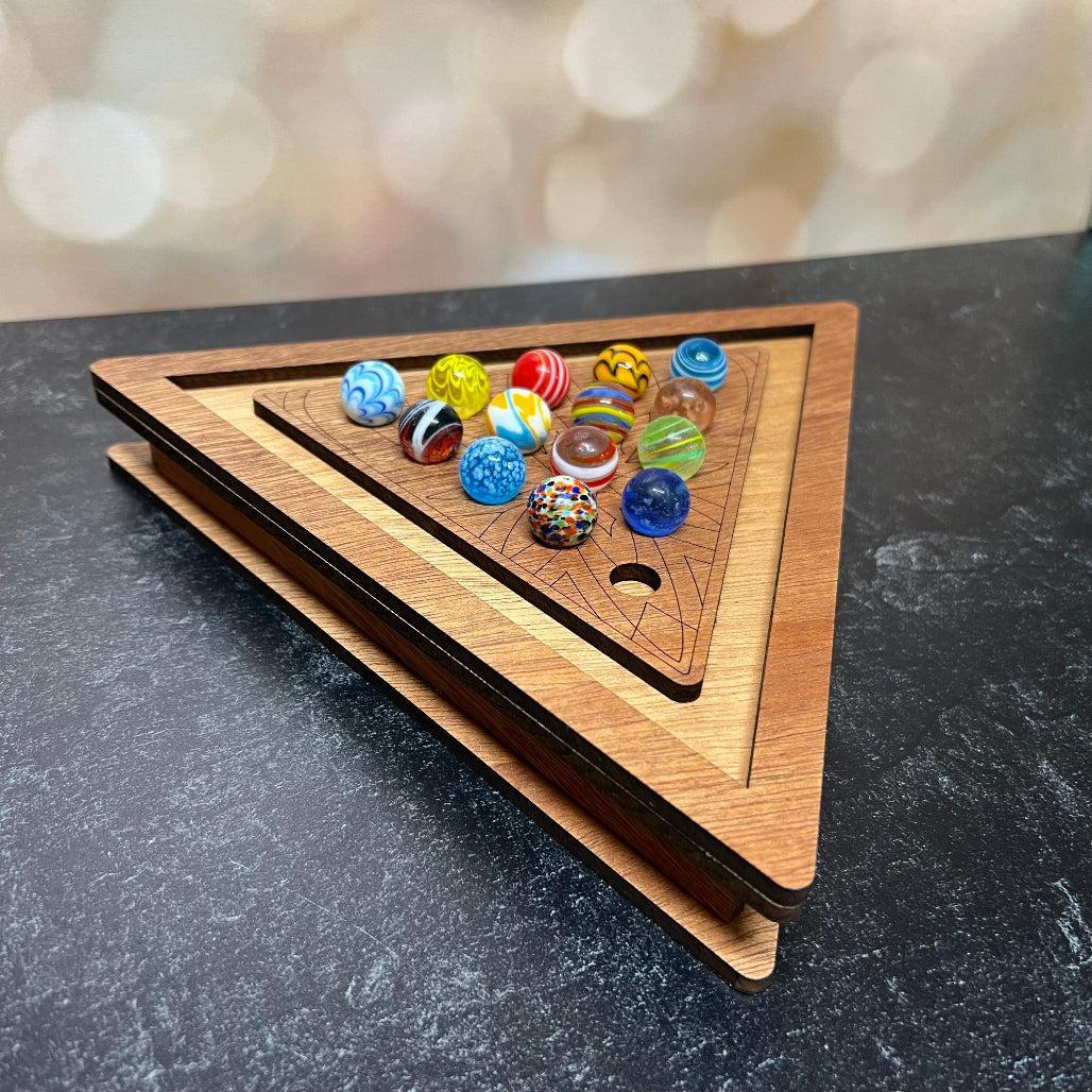 Triangular wooden marble track with colorful marbles on a dark surface