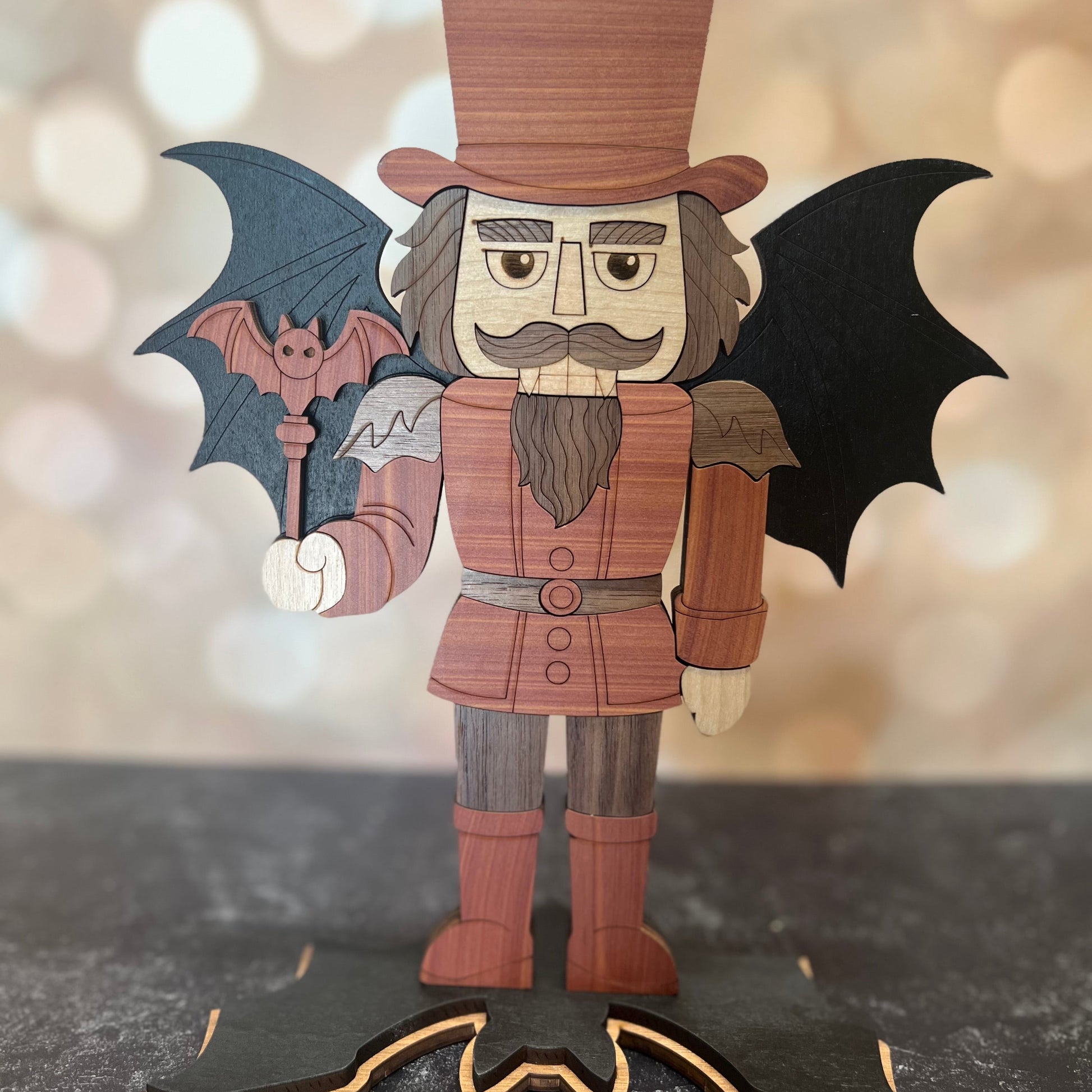 Wooden vampire figurine with bat wings on a dark surface with a blurred light background