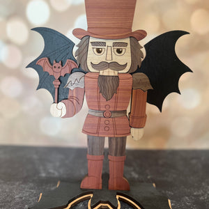 Wooden vampire figurine with bat wings on a dark surface with a blurred light background