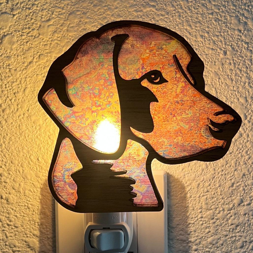 A laser-cut wooden night light in the shape of a dog's head, glowing with a warm light.