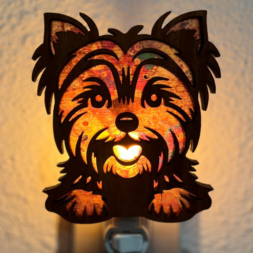 A laser-cut wooden night light in the shape of a dog's head, glowing with a warm light.