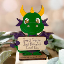Load image into Gallery viewer, Decorative dragon figurine holding a sign with motivational quote, surrounded by plants.
