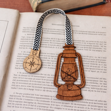 Load image into Gallery viewer, Wooden bookmark with compass and lantern design on an open book