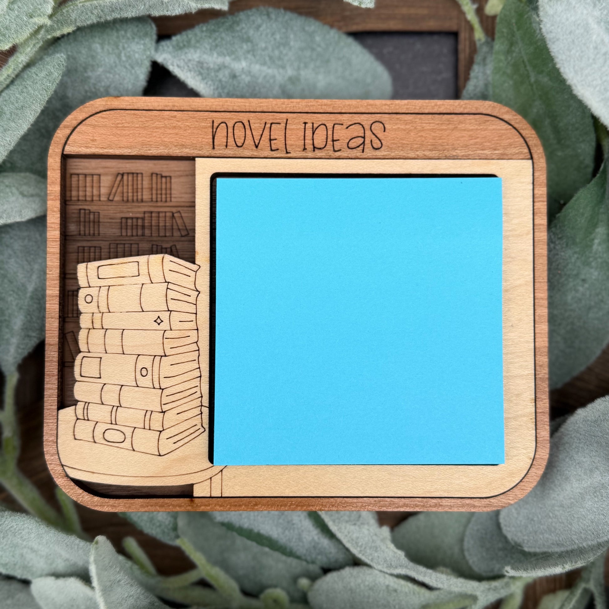 Wooden tray with blue center and book illustrations on a leafy background