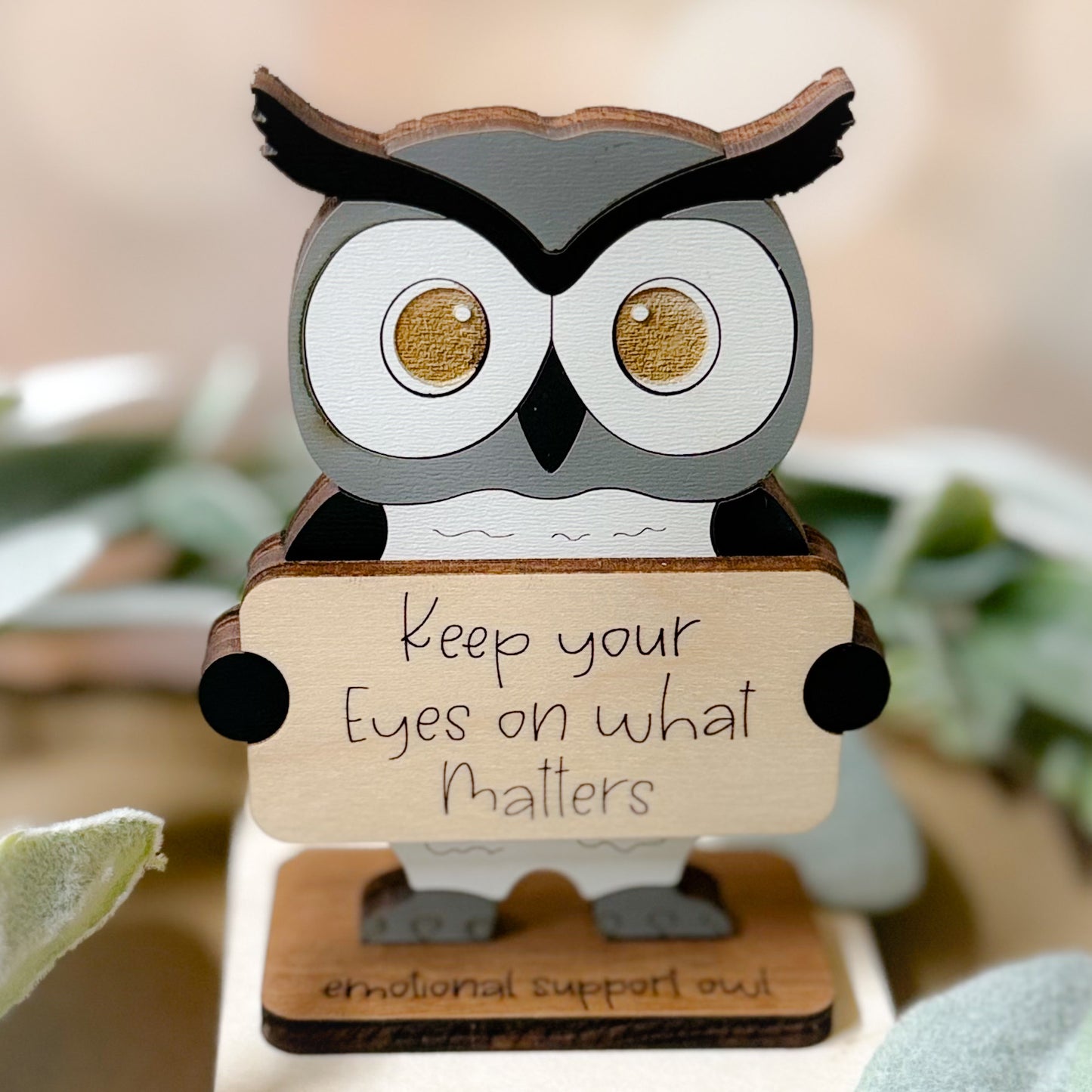 Wooden owl figurine with a motivational message on a blurred natural background