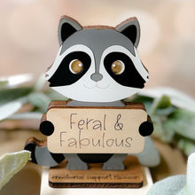 Load image into Gallery viewer, Wooden raccoon figurine with a sign saying 'Feral &amp; Fabulous' on a blurred background