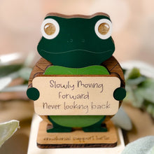 Load image into Gallery viewer, Wooden turtle figurine with a sign saying 'Slowly Moving Forward Never Looking Back' on a blurred natural background.