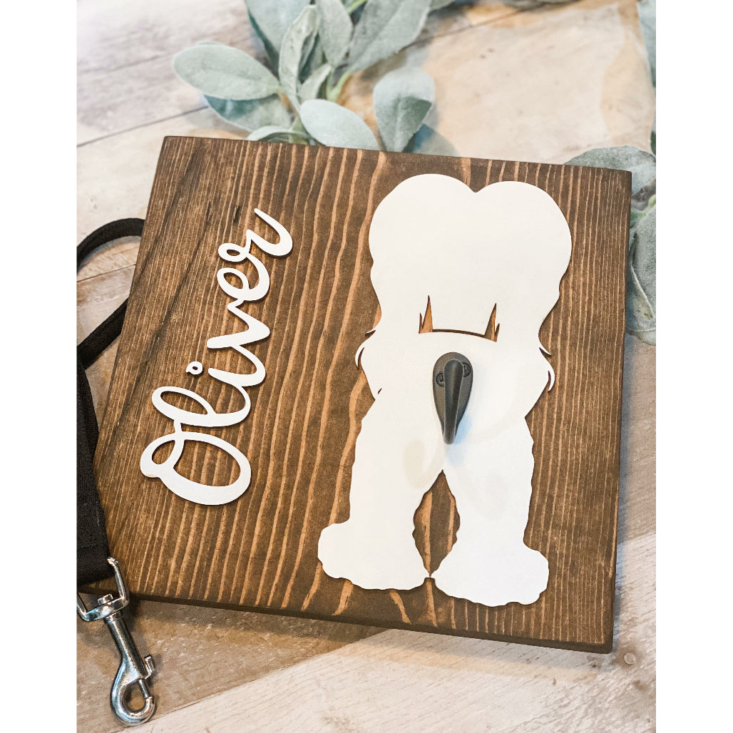 Wooden dog leash holder with white afghan hound silhouette, personalized name “Oliver,” and black metal hook on rustic wood background.