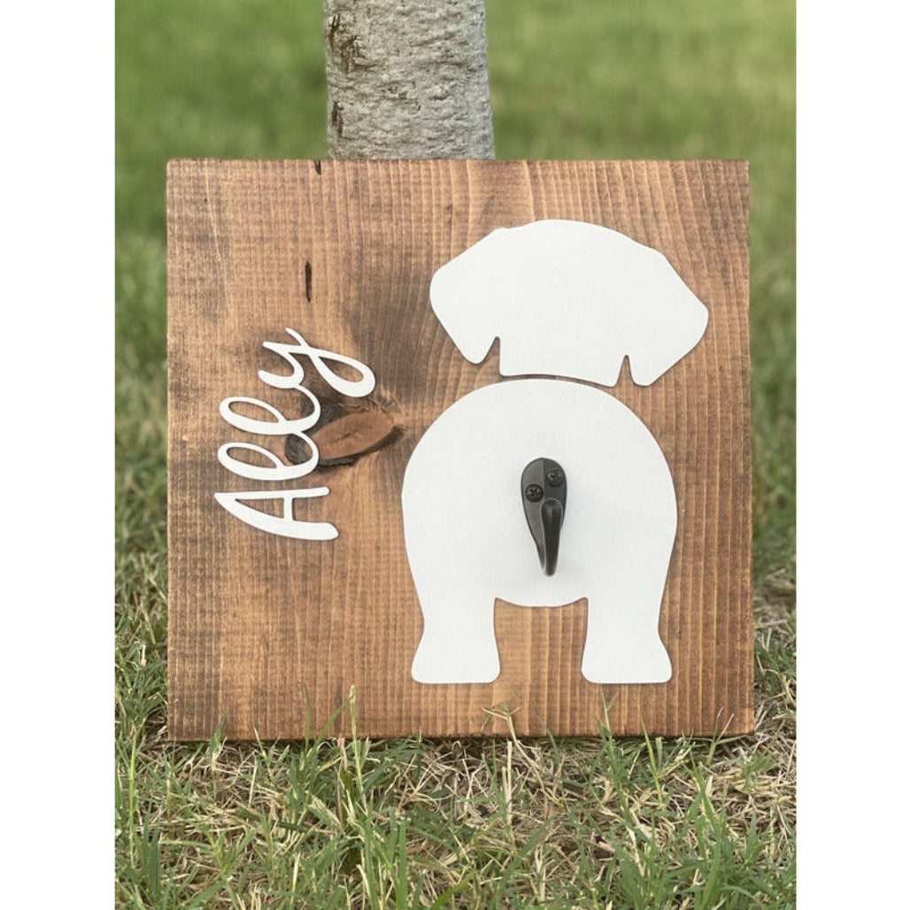 Wooden dog leash holder with white daschund silhouette, personalized name “Ally,” and black metal hook on rustic wood background.