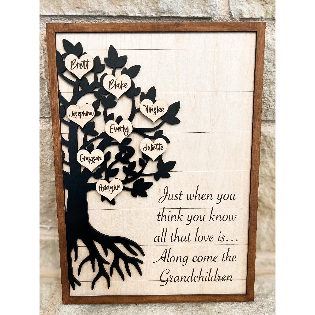 Wooden family tree wall sign with heart-shaped leaves engraved with grandchildren’s names and a quote about love and grandchildren.